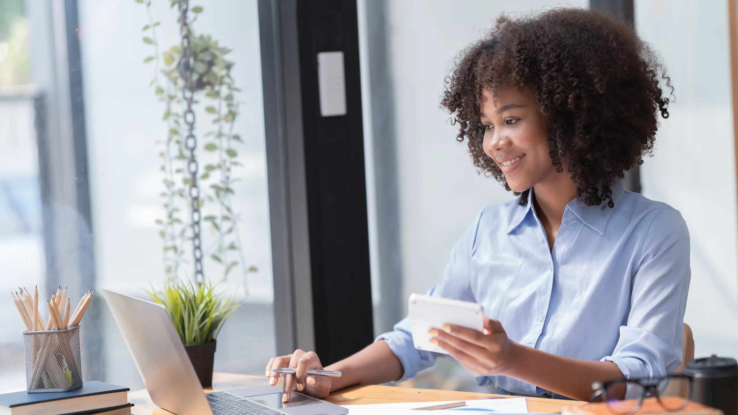 Female Entrepreneur. Cheerful African American Businesswoman Working On document and Laptop In Modern Office. Empty Space